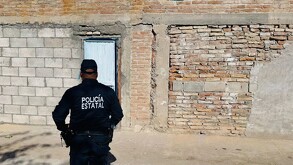 Policía frente a una vivienda de ladrillo