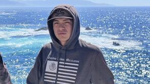 Hombre joven posando para una fotografía con una playa de fondo.