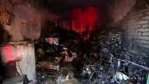 Objetos y mobiliario calcinado al interior de una cochera con escombros alrededor luego de un incendio