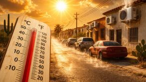 Una calle residencial bajo el sol intenso, con viviendas y aires acondicionados en funcionamiento que reflejan el calor del entorno.