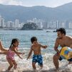 Familia disfrutando de las vacaciones de semana santa y jugando frente al mar de Acapulco con una pelota en un día soleado.