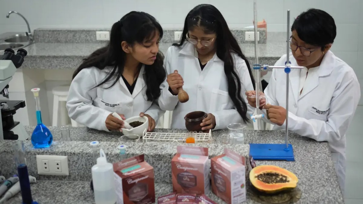 Tres alumnas de la Universidad Privada Franz Tamayo con batas blancas dentro de un laboratorio con diversos utensilios de química