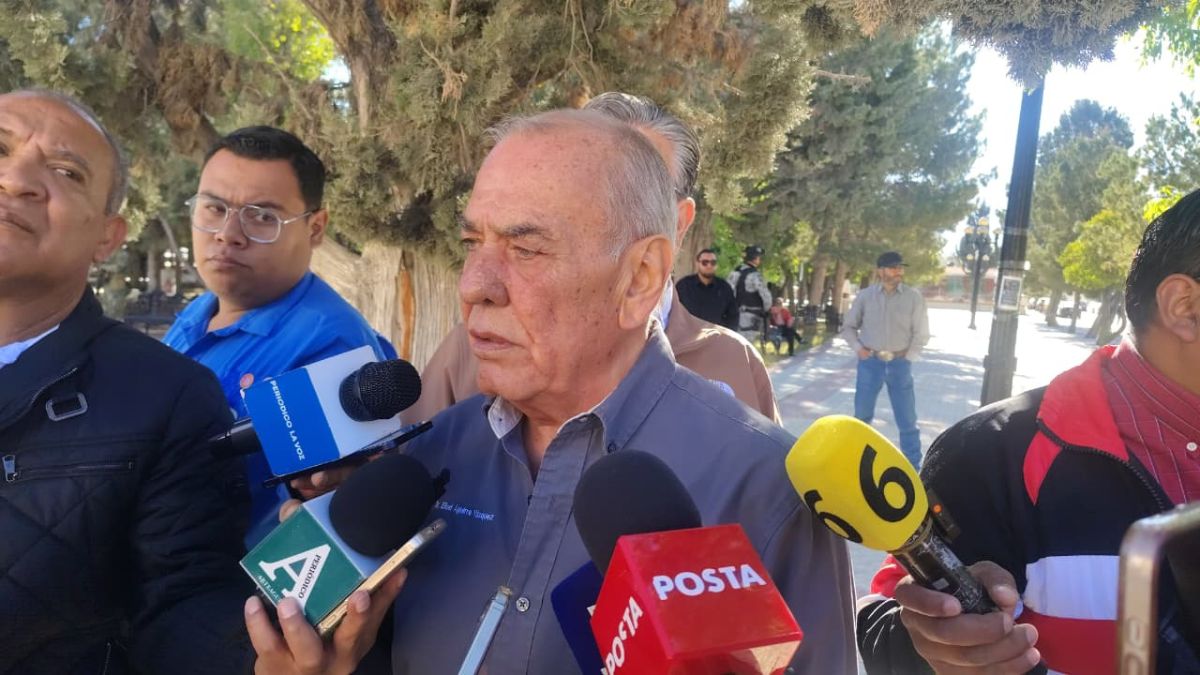 Un funcionario de salud ofrece declaraciones a medios de comunicación mientras es entrevistado por varios reporteros en un espacio público.