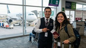 Persona en aerolínea a punto de tomar un vuelo, de fondo avión de la línea Volaris