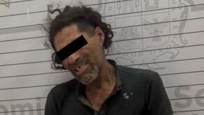 Un hombre es captado frente a una pared con líneas de medición, con las manos sujetas por esposas y en aparente estado de alteración, durante un procedimiento d