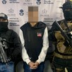 Hombre detenido con la cara censurada en medio de dos oficiales de la Fiscalía de Jalisco portando armas largas
