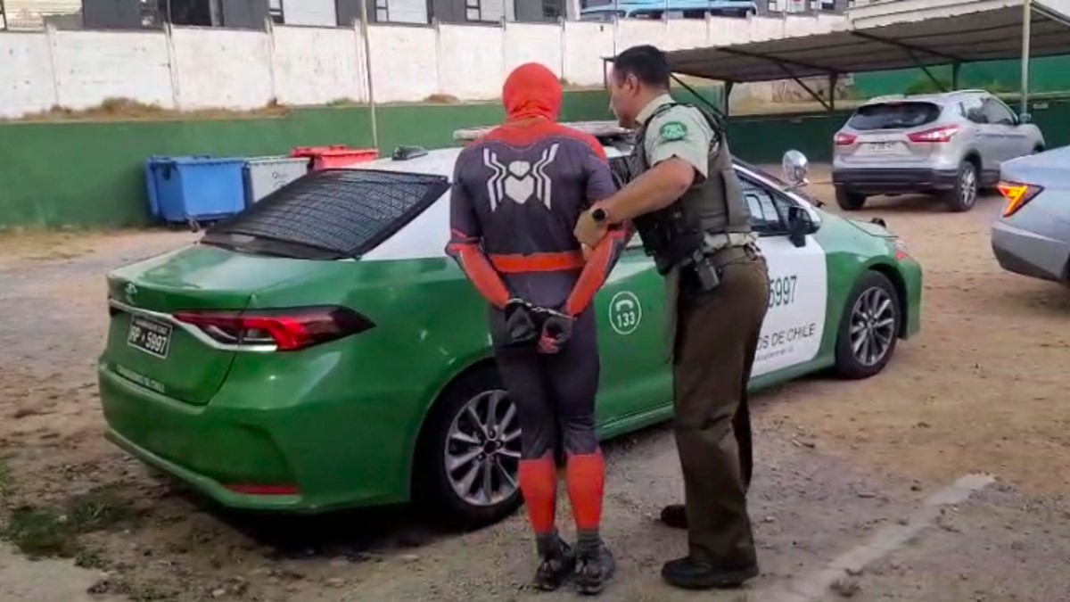 Oficial de Carabineros de la Región de Valparaíso deteniendo a un hombre disfrazado como Spider-Man y llevándolo a una patrulla