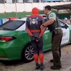 Oficial de Carabineros de la Región de Valparaíso deteniendo a un hombre disfrazado como Spider-Man y llevándolo a una patrulla