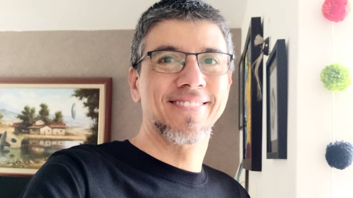 Tonatiuh Moreno, creador de CuriosaMente, viendo de frente a la cámara mientras sonríe con cuadros de fondo