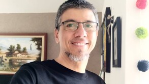 Tonatiuh Moreno, creador de CuriosaMente, viendo de frente a la cámara mientras sonríe con cuadros de fondo