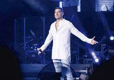 El cantante Carlos Rivera durante una presentación en vivo sobre el escenario, con iluminación azul y micrófono en mano.