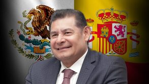 Hombre vestido de traje sobrepuesto a las banderas de España y México.