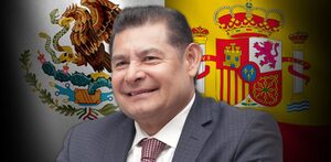 Hombre vestido de traje sobrepuesto a las banderas de España y México.