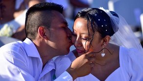 Pareja de esposos se dan un beso durante su boda.