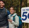 Un hombre y una mujer en el bosque mientras sotienen un celular cada uno