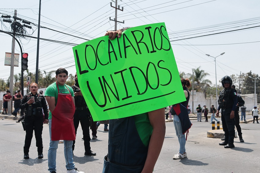Comerciante protesta con una pancarta en la mano.
