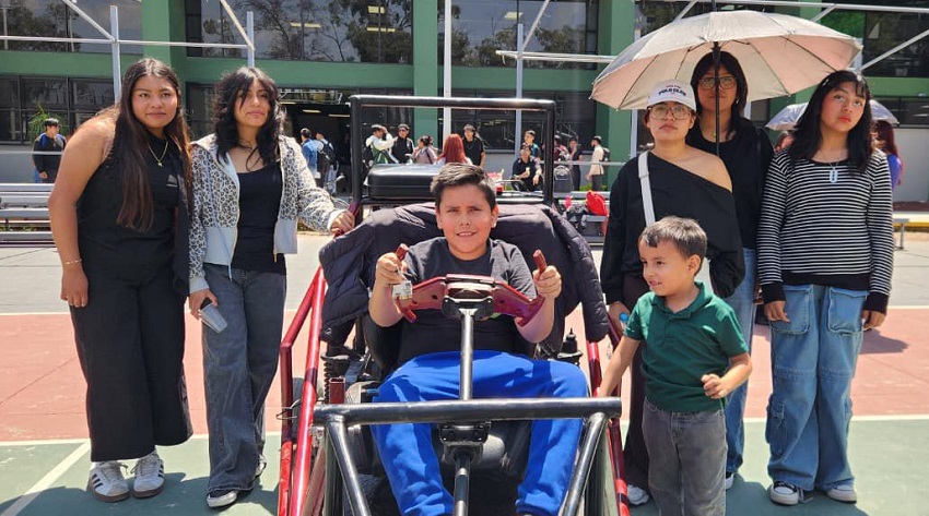 Niño montado en un vehículo motorizado junto a otras personas sonriendo.