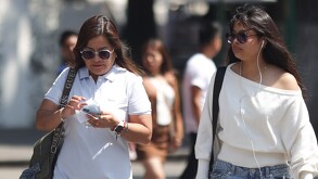 Mujeres con gafas caminando bajo el sol en el zócalo de Puebla.