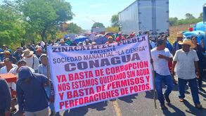 Personas se manifiestan en una carretera mientras cartan una lona.