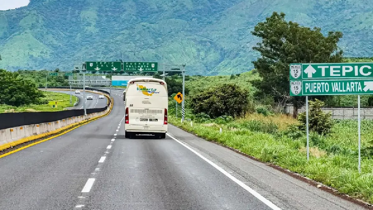 Camión de pasajeros de Vallarta Plus circulando en la carretera Guadalajara-Tepic con la vista de un cerro al frente
