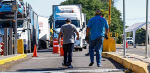 Dos personas en una autopista junto a varios tractocamiones.