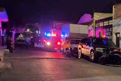 Patrulla de la Policía Municipal de Tonalá con las sirenas encendidas al exterior de unas casas con autos alrededor