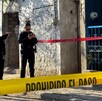 Oficiales de la Policía de Zapopan delante de una casa con portón azul acordonada con cintas policiacas