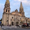 Vista del exterior de la Catedral de Guadalajara con calandrias tiradas por caballos y personas caminando alrededor