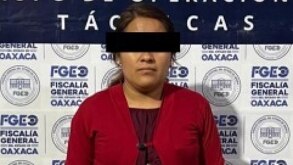 Mujer vestida de rojo presentada ante autoridades de Oaxaca luego de ser detenida.
