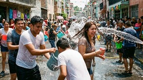 Gente mojándose con cubetas y mangueras. FOTO IA
