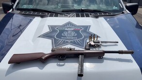 Pistola tipo revolver y un arma larga calibre .22 con municiones colocados sobre el cofre de una patrulla de la Policía Municipal de Guadalajara