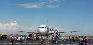 Avión en pista de aterrizaje con varias personas descendiendo.