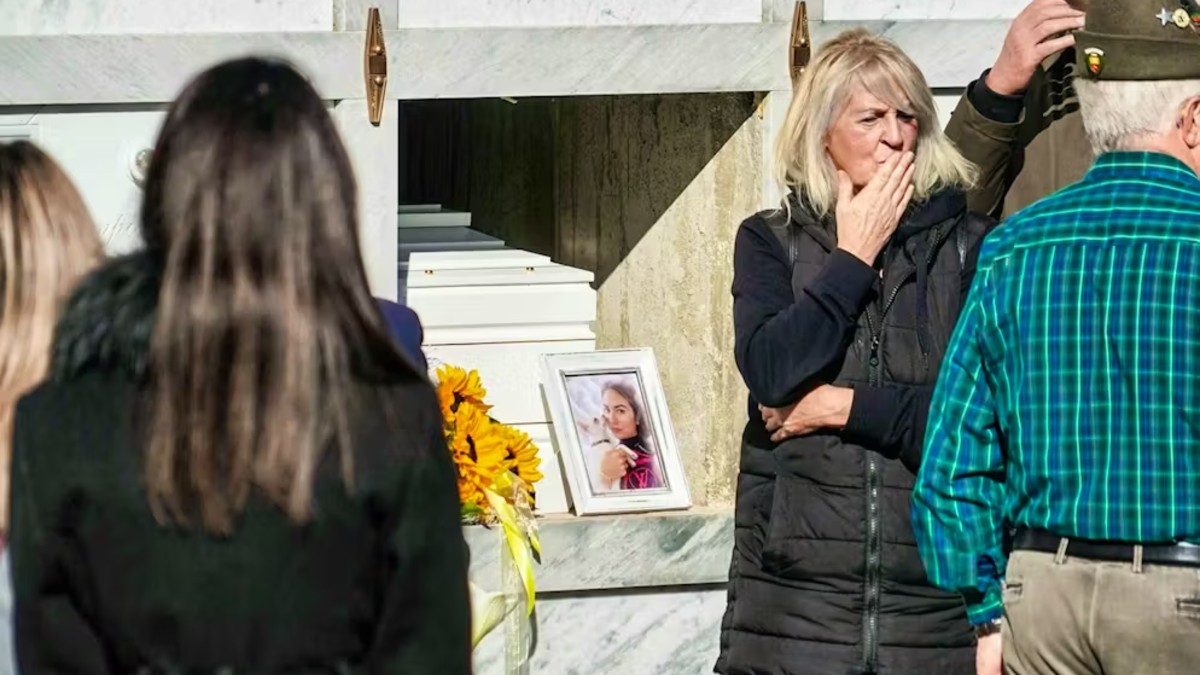 Personas alrededor de la tumba de Pamela Genini con una fotografía de ella y su perro al lado de un ramo de girasoles