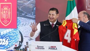 Dos hombres sostienen una camiseta de la Selección de Fútbol de España mientras sonríen.