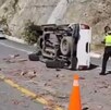Elementos de policía parados junto a una camioneta volcada en una carretera.