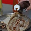 Persona sirve salsa sobre un taco servido en una charola.