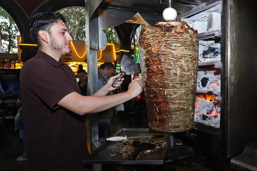 Persona cortando un trompo de carne en movimiento.