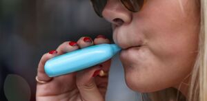 Imagen de joven sosteniendo un vapeador mientras se encuentra en clases.