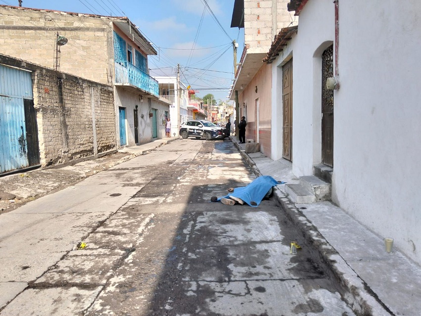 Cadáver de una persona tapada con una cobija azul en vía pública.