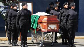 Mujeres policías formadas junto a un féretro con el cuerpo de un compañero fallecido.