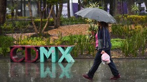 Una mujer se protege de las constantes precipitaciones registradas esta tarde en la capital.