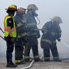 Se observa a unos bomberos sofocando un incendio, se ve humo.