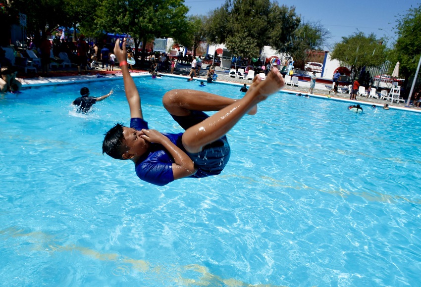 Joven se tapa la nariz mientras se arroja a una alberca.