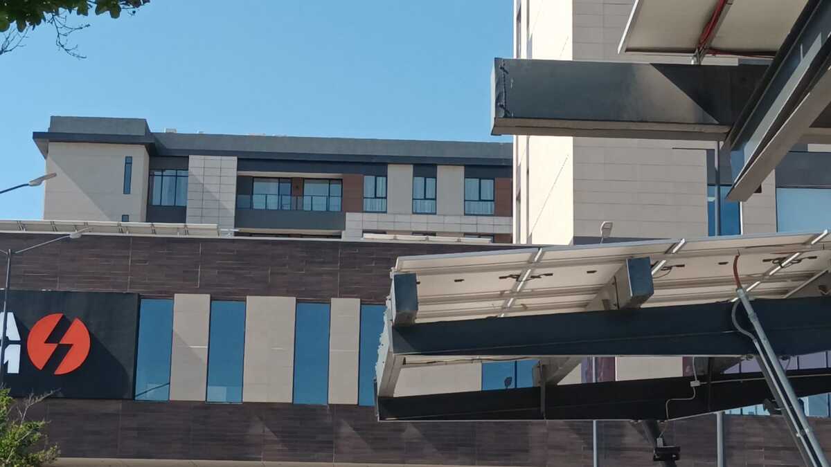 Conjunto habitacional moderno con fachada de tonos neutros y estructuras metálicas en primer plano.