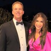 Kristi Noem vistiendo un vestido rosa junto a su esposo Bryon Noem vestido de traje delante de un jardín