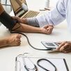 Un médico tomando la presión de un joven en su brazo izquierdo con un tensiómetro electrónico