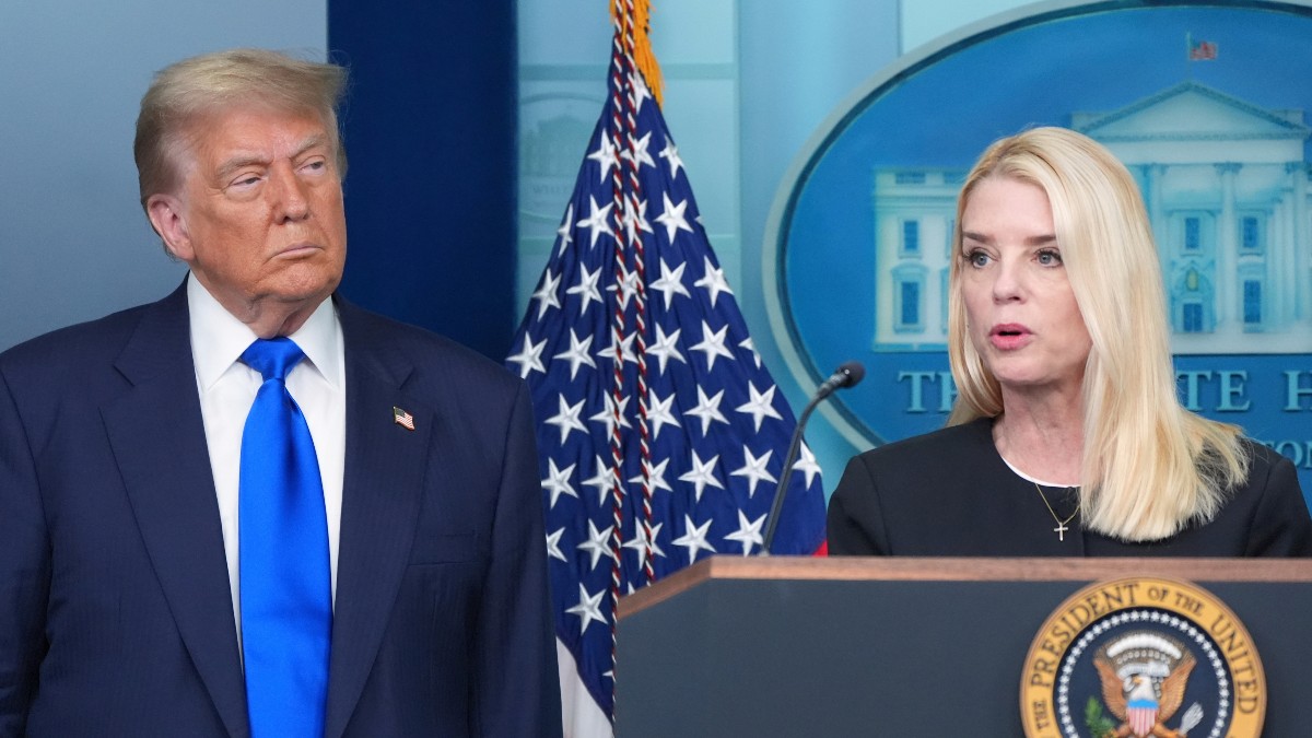 Pam Bondi hablando con Donald Trump de fondo.