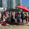 Paramédicos, elementos de Protección Civil de Puerto Vallarta y turistas rodeando a una persona en medio de la playa