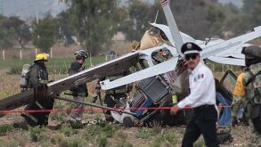 Policía camina junto a bomberos que realizan labores de rescate en una avioneta estrellada en Puebla.