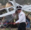 Policía camina junto a bomberos que realizan labores de rescate en una avioneta estrellada en Puebla.